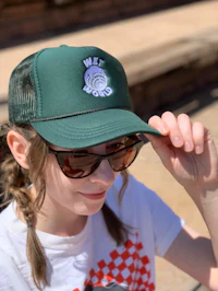 a girl wearing sunglasses and a green trucker hat